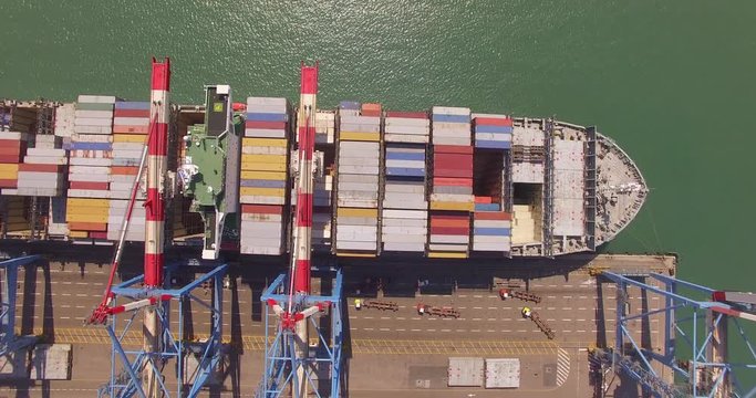 Commercial port with container ship during loading and unloading - Top down view.