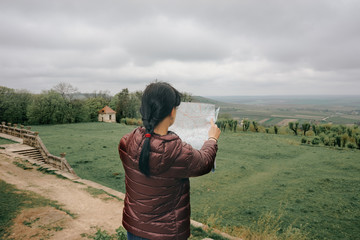 Happy girl traveler on vacation with map of landmarks, overlooking the beautiful landscape