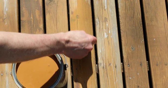 Footage of natural cedar wooden deck being stained by hand brush 