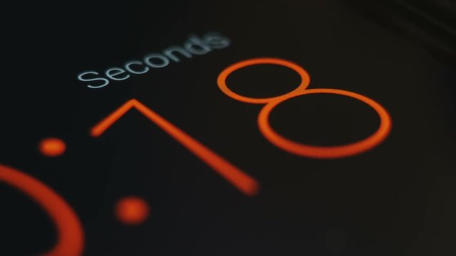 Orange thin number fonts countdown close up in black background.
Digital countdown timer in clean dark background. 
