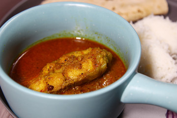 Kerala fish curry on a platter made with coconut and tamarind paste tempered with mustard seeds and fenugreek seeds, selective focus