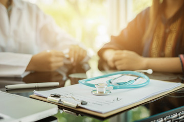 Stethoscope with clipboard and Laptop on desk,Doctor working in hospital writing a prescription, Healthcare and medical concept,test results in background,vintage color,selective focus - obrazy, fototapety, plakaty