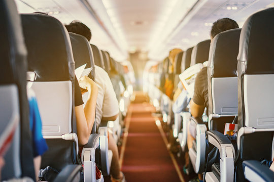 passenger seat, Interior of airplane with passengers sitting on seats and stewardess walking the aisle in background. Travel concept,vintage color,selective focus © Have a nice day 