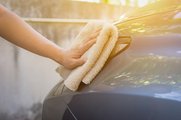 Hand with microfiber cloth cleaning leather seat,auto detailing and valeting concept,washing car...