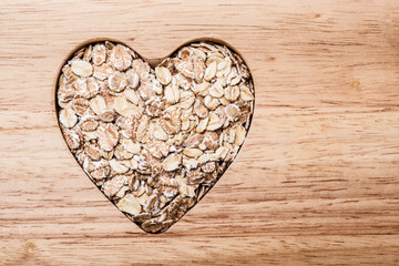 Oat cereal heart shaped on wooden surface.