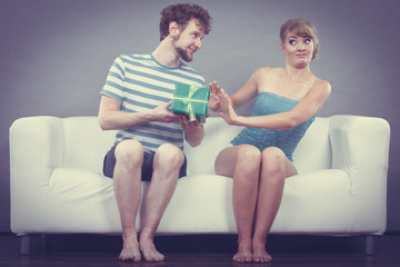 Young man giving offended woman gift box