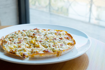 side view shot of pizza on white plate near a window
