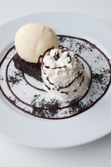 close up whip cream and vanilla ice cream on chocolate brownie serve on white dish