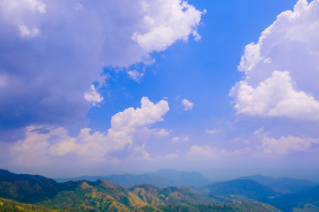 Clouds float over mountains with blue sky background