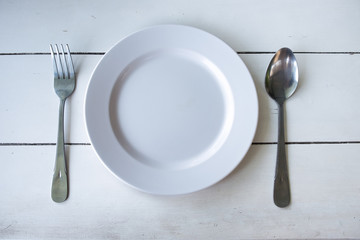 white dish, folk and spoon on white rustic wooden