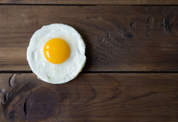 round shaped fried egg for healthy breakfast on dark wooden backgrond