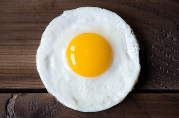 round shaped fried egg for healthy breakfast on dark wooden backgrond