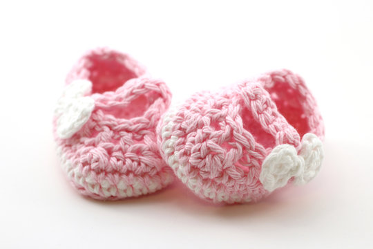 A photo of a pair of pink baby booties isolated on a white background
