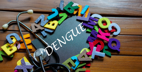 Black board written with " DENGUE " and stethoscope on wooden back ground.Image with selective focus.Medical and health care concept