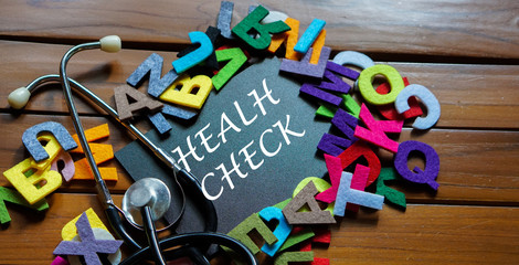Black board written with " HEALTH CHECK " and stethoscope on wooden back ground.Image with selective focus.Medical and health care concept.