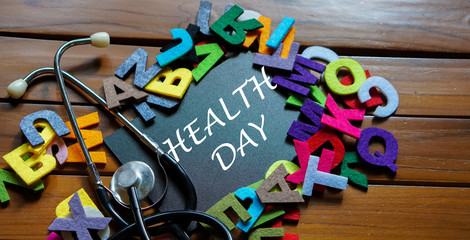 Black board written with " HEALTH DAY " and stethoscope on wooden back ground.Image with selective focus.Medical and health care concept.