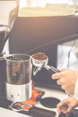 Barista holding portafilter with ground coffee in cafe for prepare to make espresso coffee.