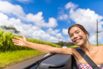 Car road trip woman freedom with hand floating in the wind. Asian girl sitting in convertible...