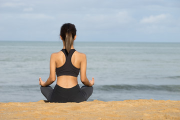 Fototapeta na wymiar Young woman practicing yoga on the beach