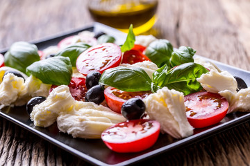 Caprese Salad.Mediterranean salad. Mozzarella cherry tomatoes basil and olive oil on old oak table. Italian cuisine.