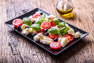 Caprese Salad.Mediterranean salad. Mozzarella cherry tomatoes basil and olive oil on old oak table. Italian cuisine.