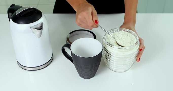 Video footage of woman hands making a cup of hot milk on the table in the kitchen, shot in 4k resolution