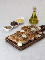 Chicken legs in marinade with olive oil on a wooden board. 