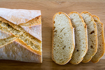 Slices and loaf of bread on wooden table.