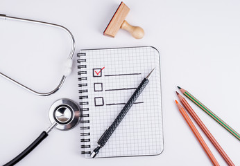 Book with blank checklist on a white office desk.