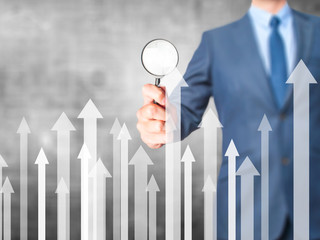 Sales Growth Graph - Business man holding magnifying glass on screen interface