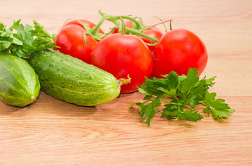 Branch of the red tomatoes, two cucumbers and parsley closeup