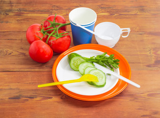 Disposable cutlery and several vegetable on wooden surface