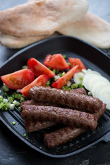 Close-up of grilled cevapi or cevapcici sausages, selective focus, studio shot