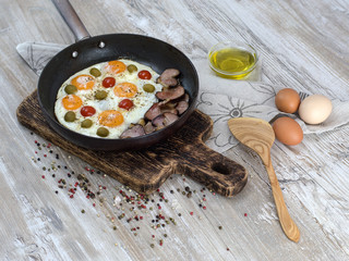 fried eggs with bacon, olives and tomatoes a hearty breakfast. 
