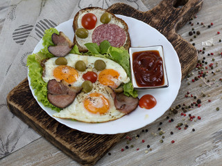 fried eggs with bacon, olives and tomatoes a hearty breakfast. 