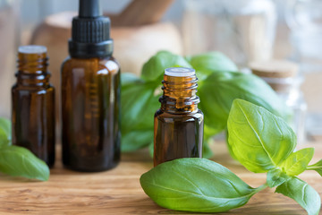 A bottle of basil essential oil with fresh basil leaves