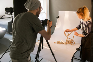 Creative team shooting still life. Back view of photographer taking object shots with assistant in...