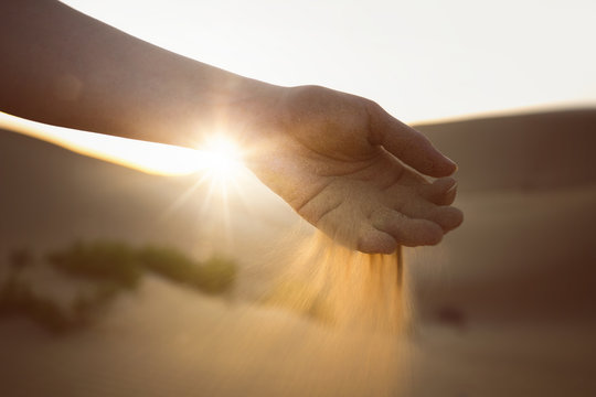 Sand gleitet durch eine Hand 
