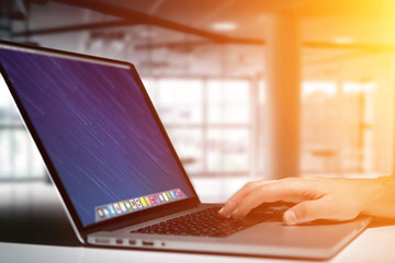 Hand typing on a keyboard of laptop with operating system screen on background
