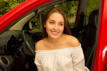 Plakat Beautiful sexy young woman inside of a red car smiling and wearing a white blouse