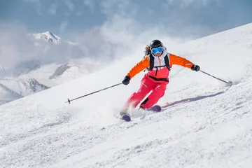 Foto op Plexiglas Wintersport Vrouwelijke skiër op een helling in de bergen