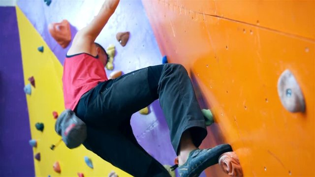 Climber Man On Artificial Climbing Wall In Bouldering Gym Without Insurance. Close Up