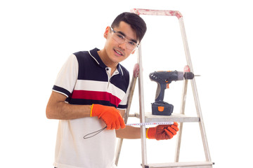 Young man with electric screwdriver and ledder