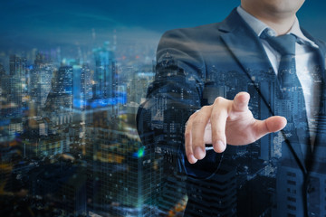 Double exposure of professional businessman touch digital screen with cityscape of business in...