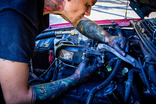 Man With Tattoos Working On Car Engine