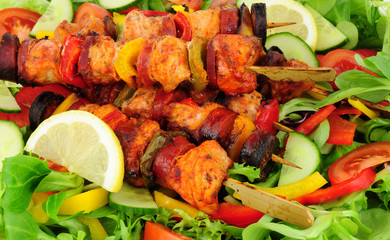 Chicken and spicy chorizo sausage kebabs with sweet peppers on a salad background
