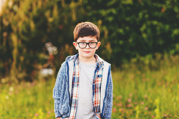 Outdoor portrait of cute 6 year old little boy in the park