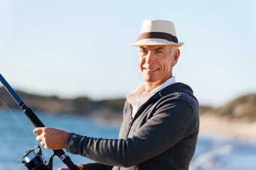 Senior man fishing at sea side