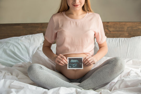Young preganant woman expecting a baby relaxing on bed indoors
