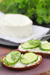 Sandwiches with soft cheese, cucumbers and greens